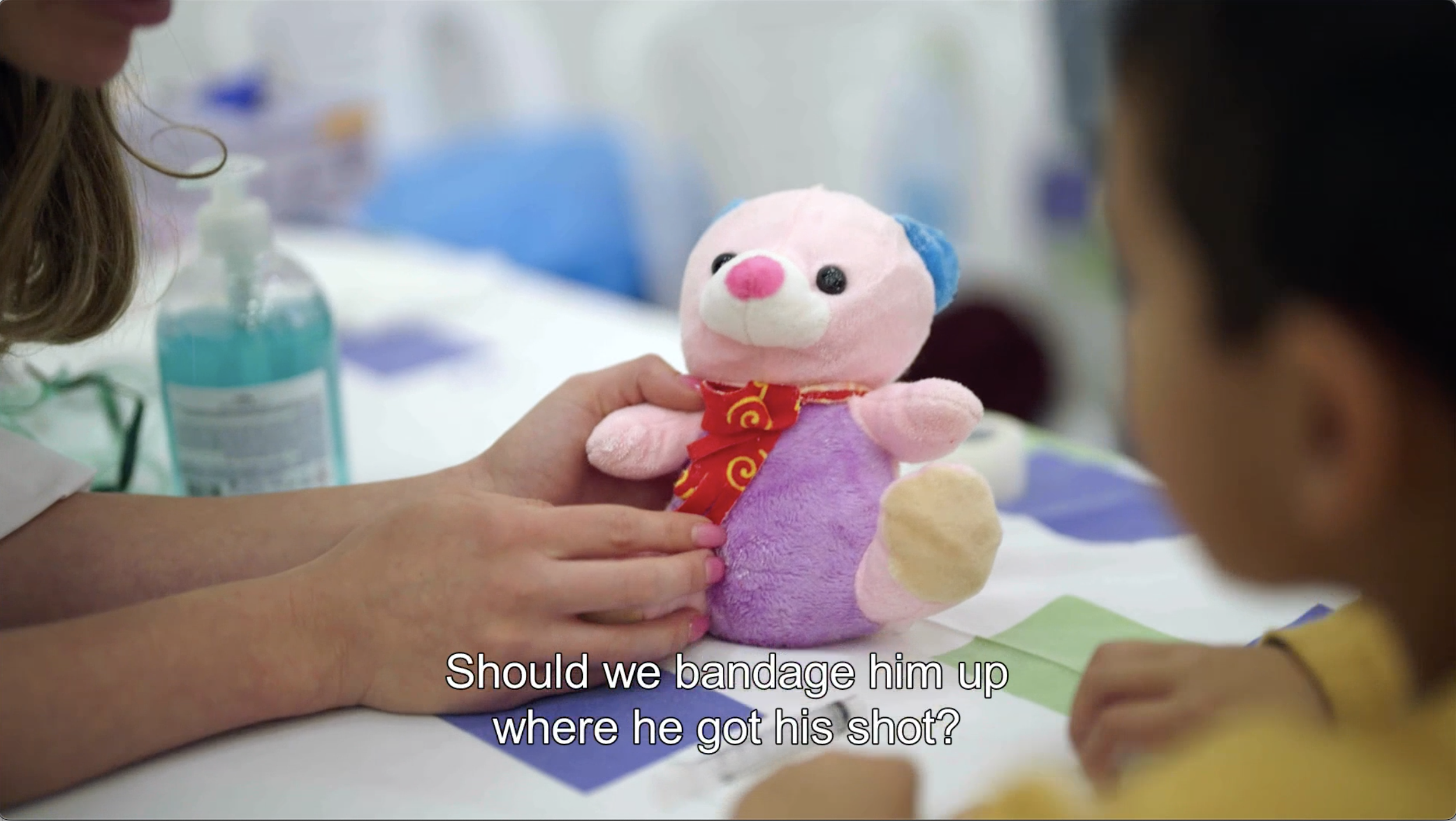 A student and a little girls are taking care of a teddy bear